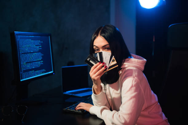 young teenager hacker girl in hoodie holding credit card violating private password holding credit card in cybercrime and cyber crime concept and internet information security concept.