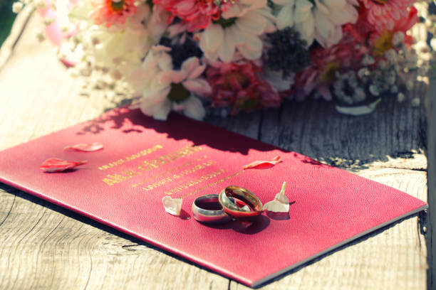 Close-Up Of Wedding Rings On Red Book Over Table